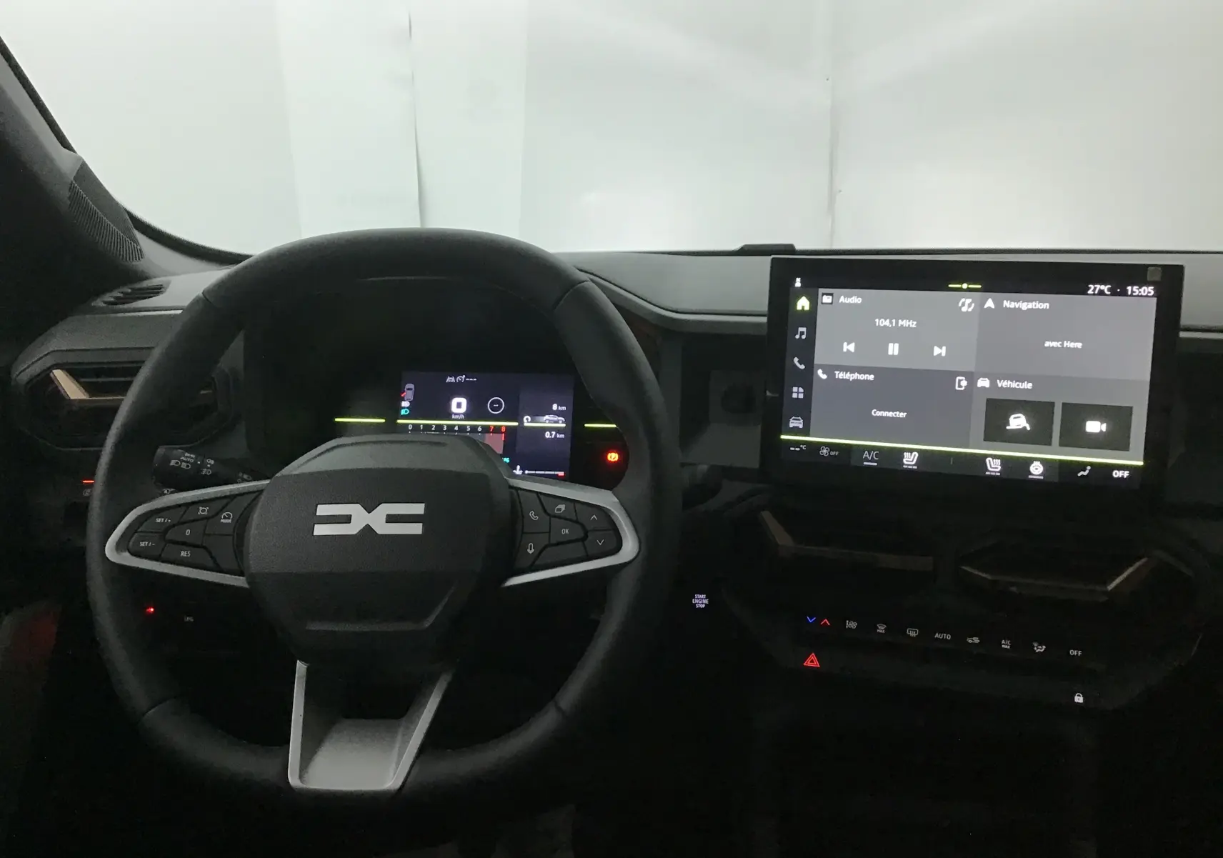 Vue intérieure du tableau de bord du Dacia Duster 2025 avec volant multifonction et écran tactile central allumé.