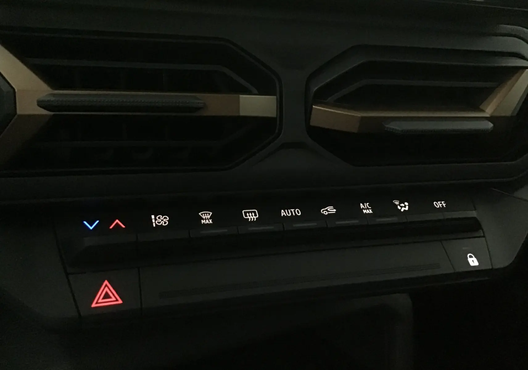 Panneau de commandes climatisation et alertes du tableau de bord du Dacia Duster 2025 kaki, avec touches rétroéclairées.