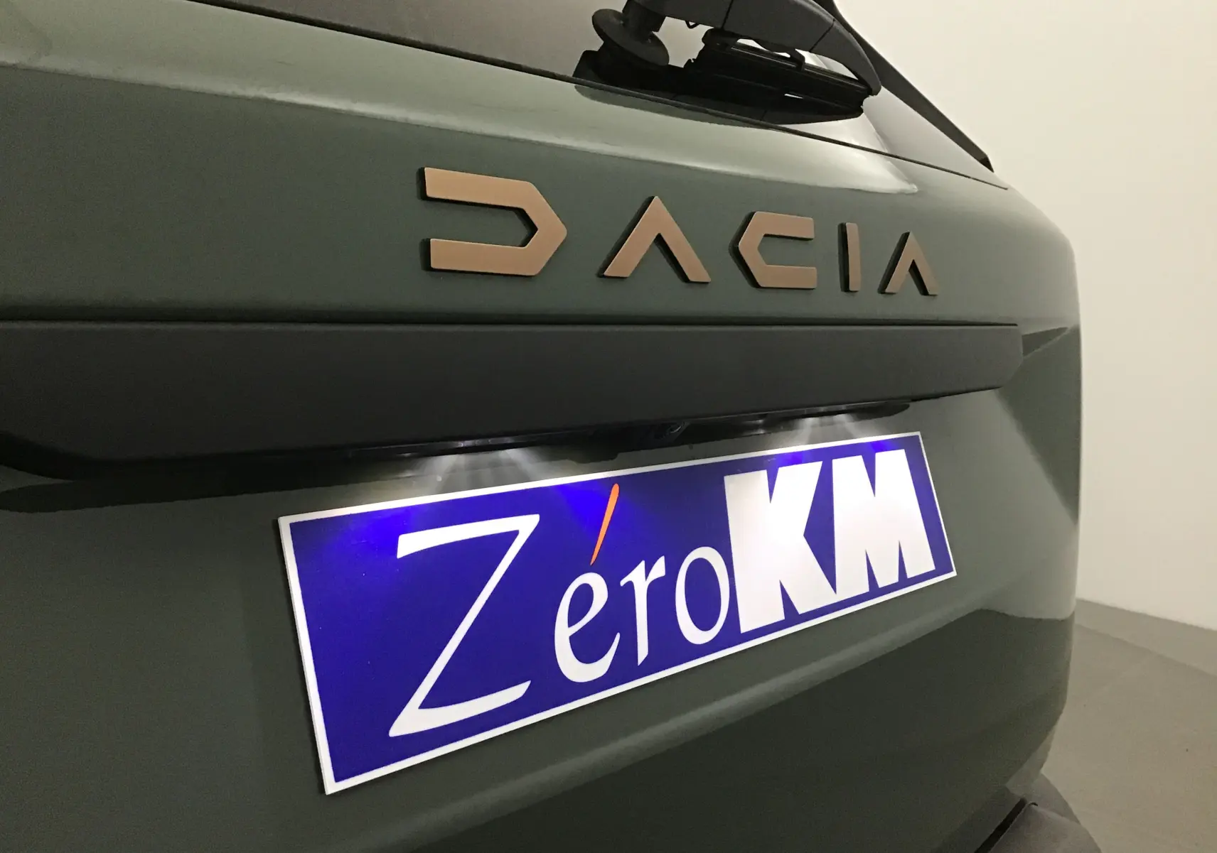 Gros plan sur l'arrière kaki lichen du Dacia Duster 2025 avec logo DACIA et plaque Zéro KM visible.