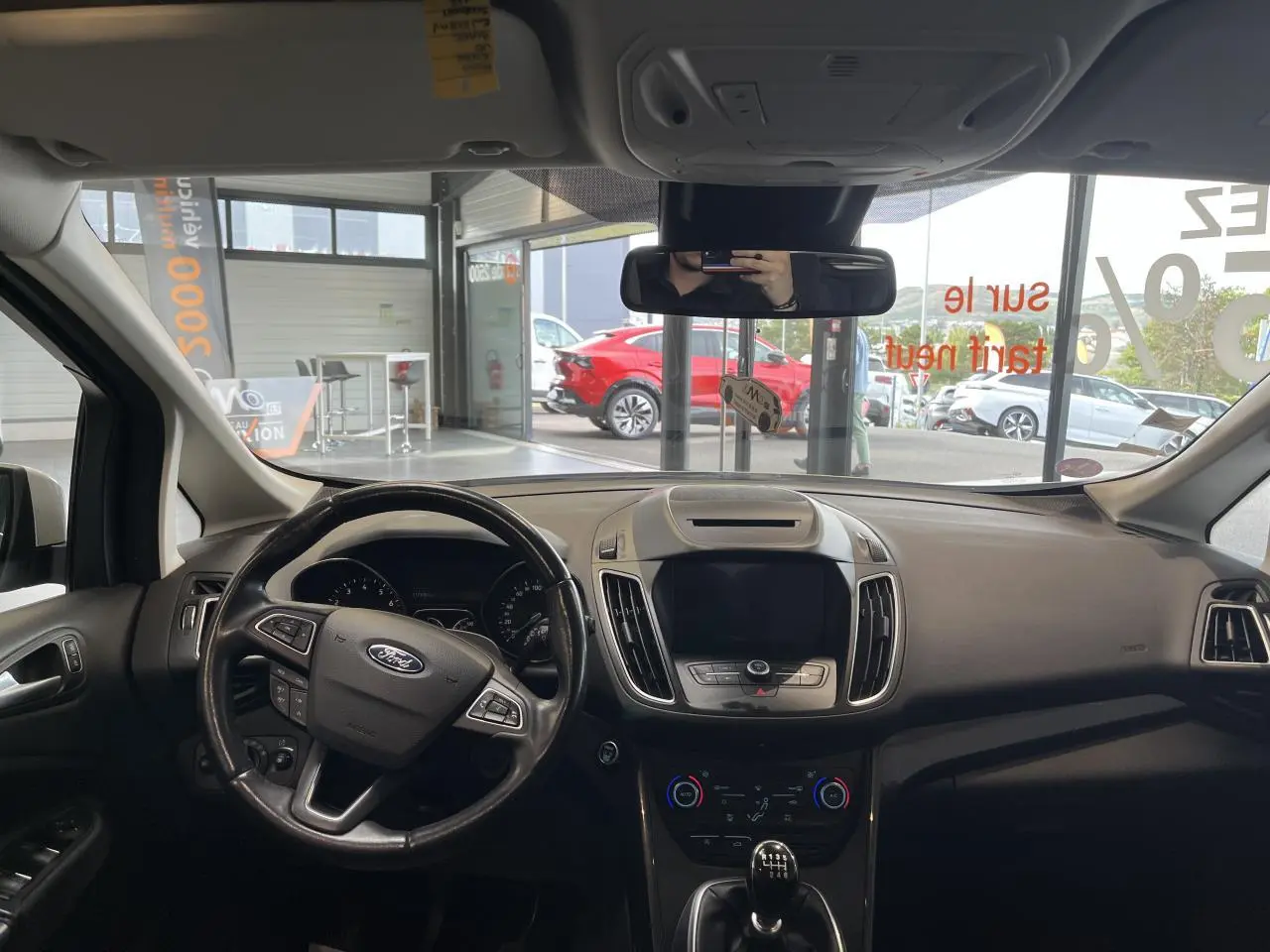 Vue intérieure frontale du tableau de bord et volant cuir noir de la Ford C-MAX blanc, avec écran tactile éteint.