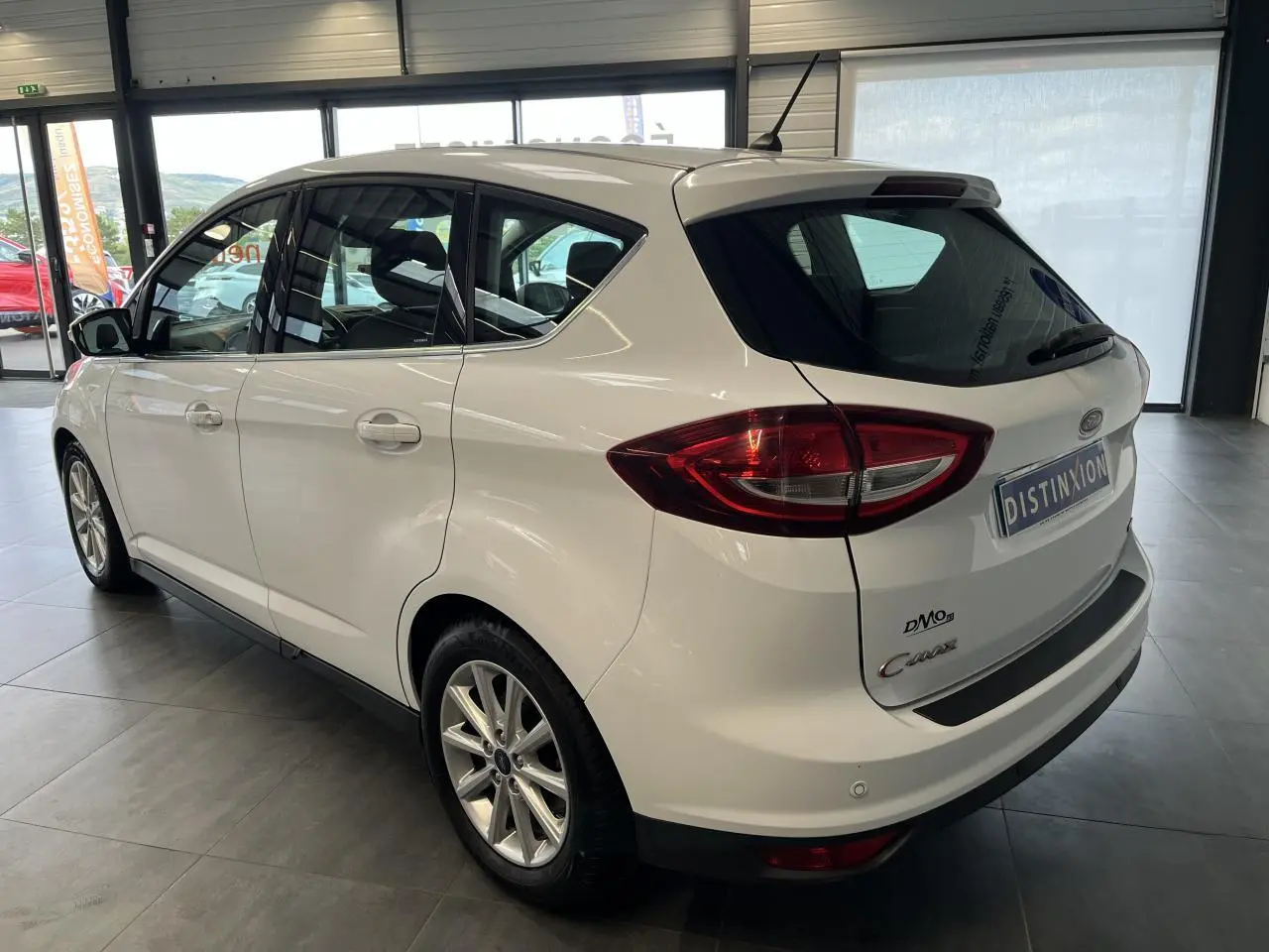 Vue 3/4 arrière droit d'un Ford C-MAX blanc avec jantes alliage et toit panoramique en showroom.