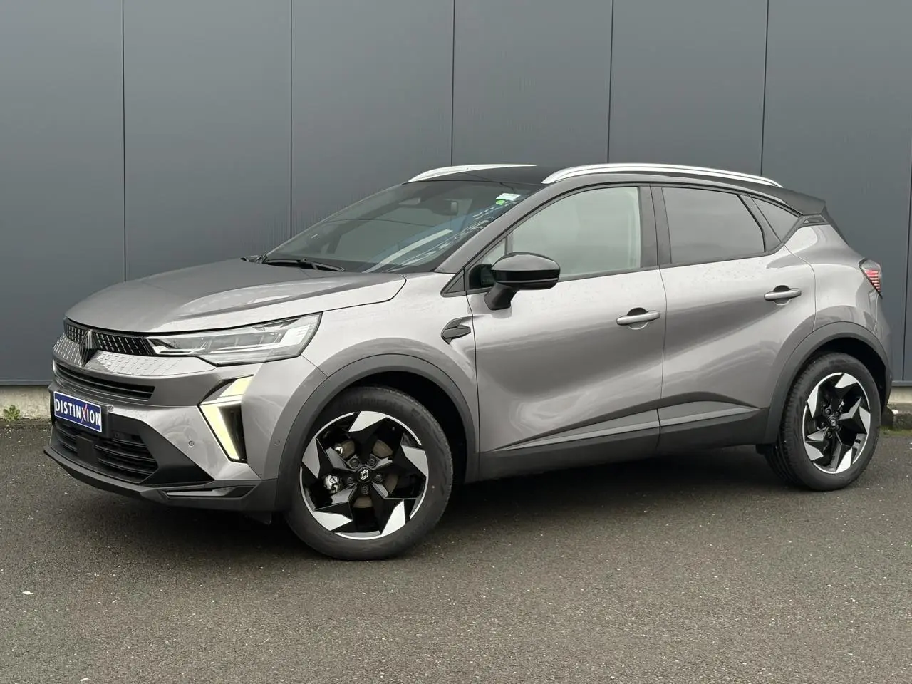 Renault Captur 2025 gris Cassiopée et noir, vue 3/4 avant droit avec jantes alu noires diamantées et railing de toit alu.