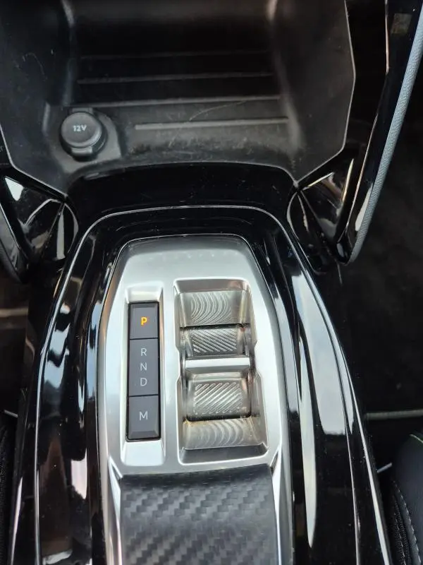 Vue rapprochée de la console centrale noire du Peugeot 2008 Hybrid 145 e-DCS6 GT avec sélecteur de boîte auto et prise 12V.