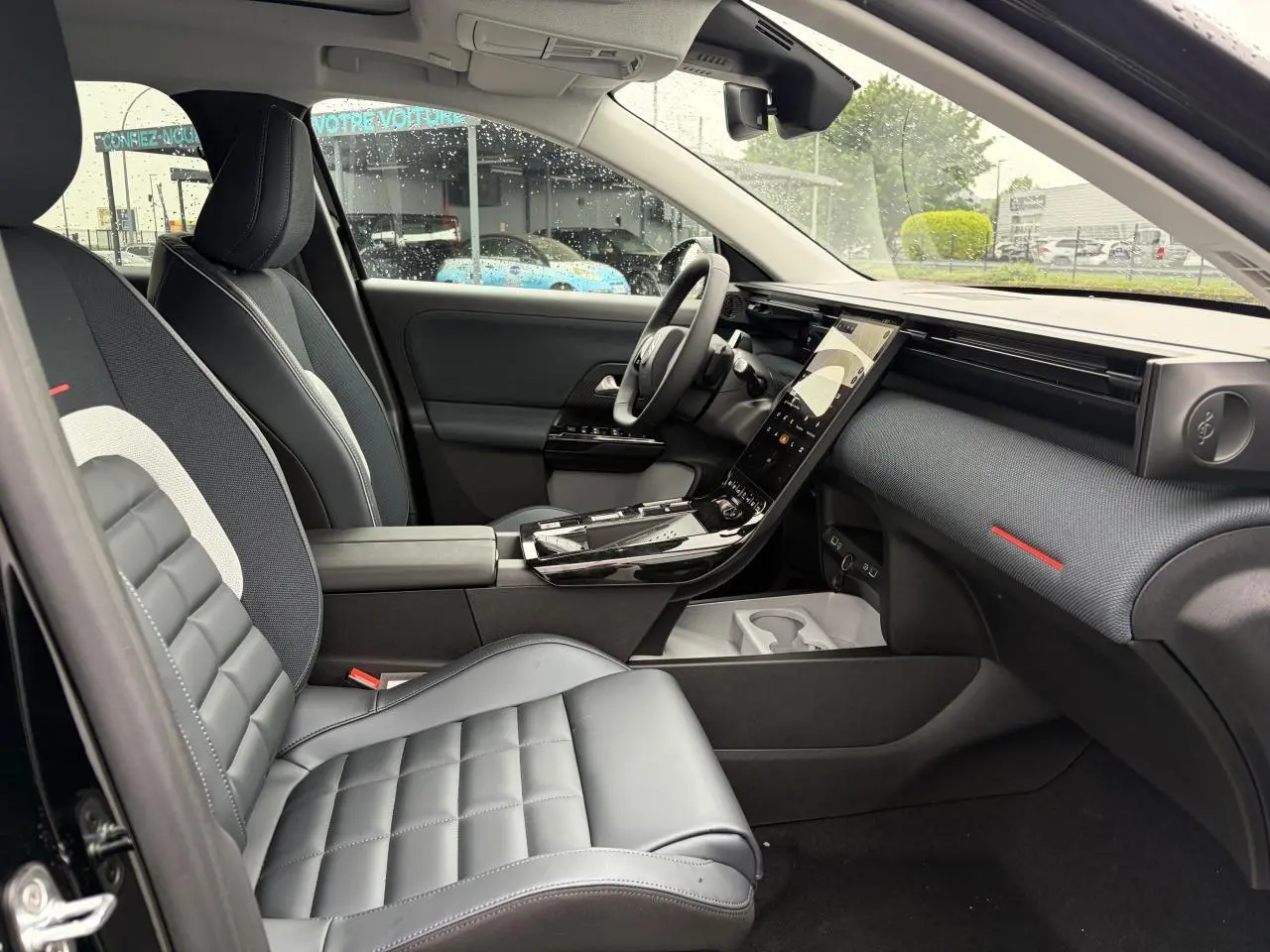 Intérieur avant droit du Citroën C5 Aircross noir métal, avec sellerie cuir et tissu bleu, tableau de bord moderne et écran tactile vertical.