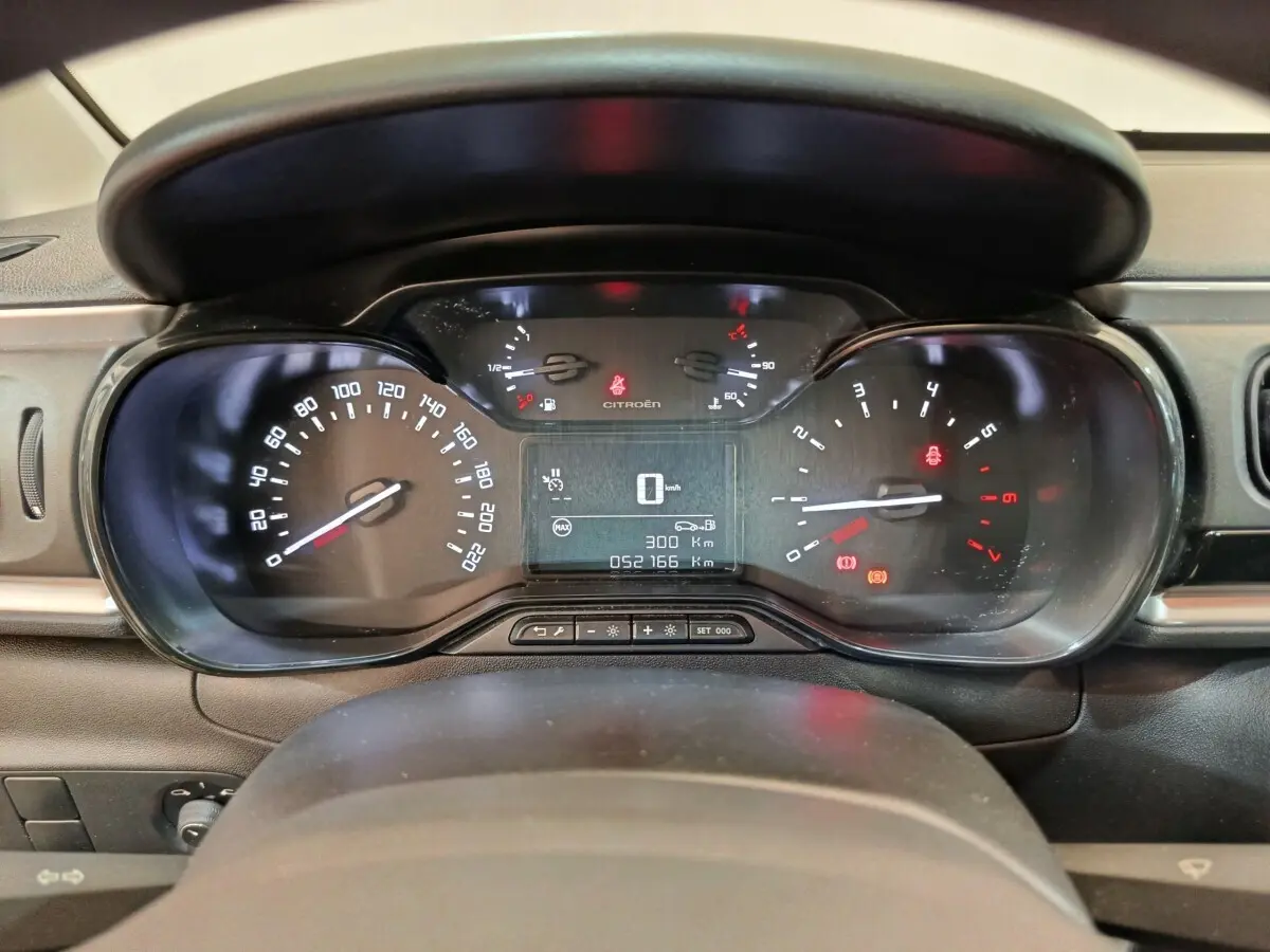 Vue rapprochée du tableau de bord numérique de la Citroën C3 blanche, affichant vitesse et jauges.