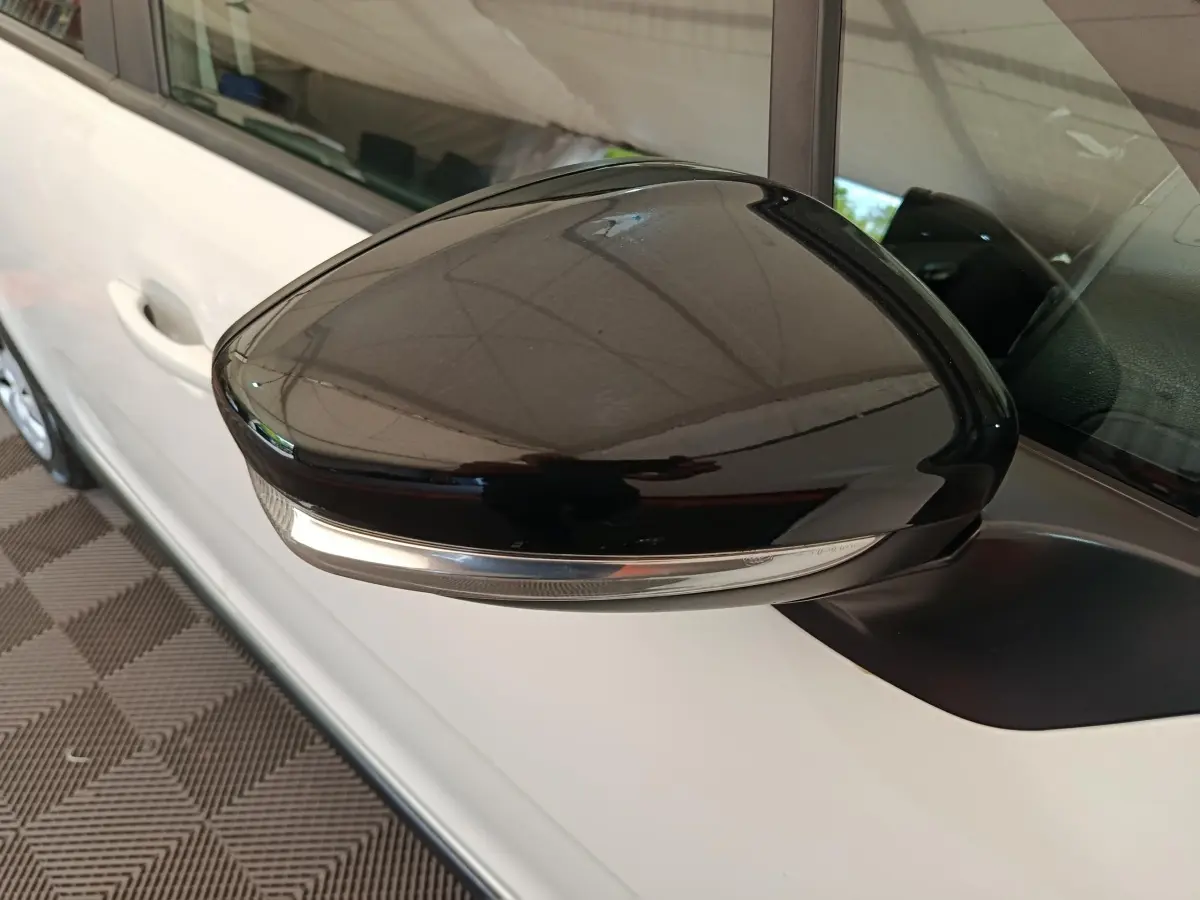 Rétroviseur noir brillant côté conducteur d'une Citroën C3 blanche 2020, avec clignotant intégré.