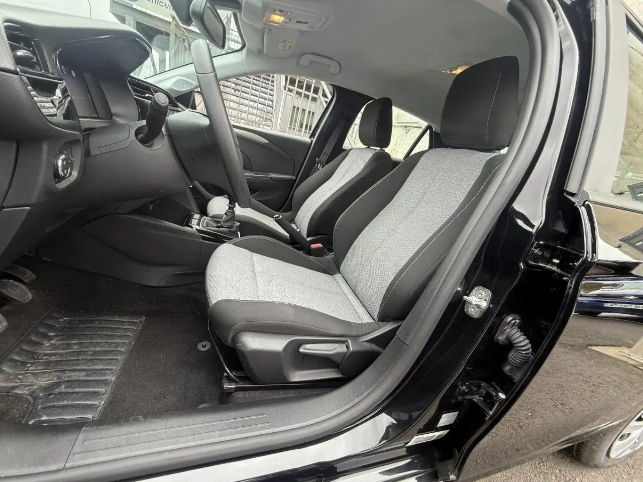 Vue intérieure côté conducteur de l’Opel Corsa 2025 noir karbon, montrant les sièges bi-ton gris et noir et le tableau de bord.