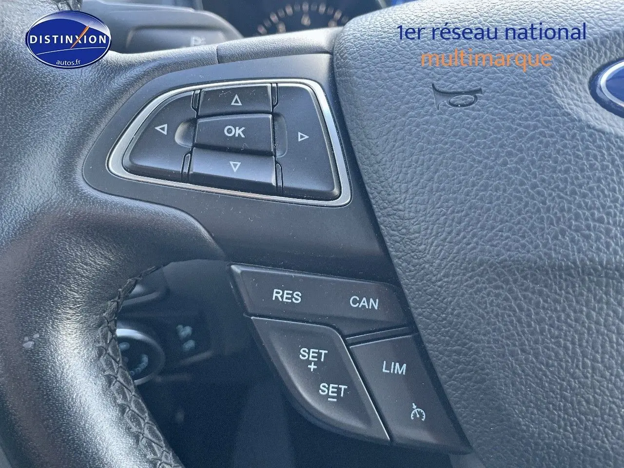 Gros plan sur le volant en cuir noir d'une Ford Focus SW gris magnetic, avec commandes multifonctions visibles.