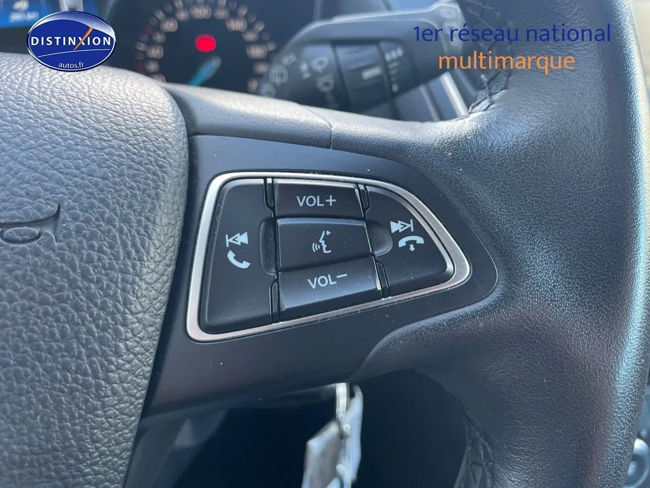 Gros plan sur les commandes audio au volant en cuir noir d'une Ford Focus SW gris magnetic de 2018.