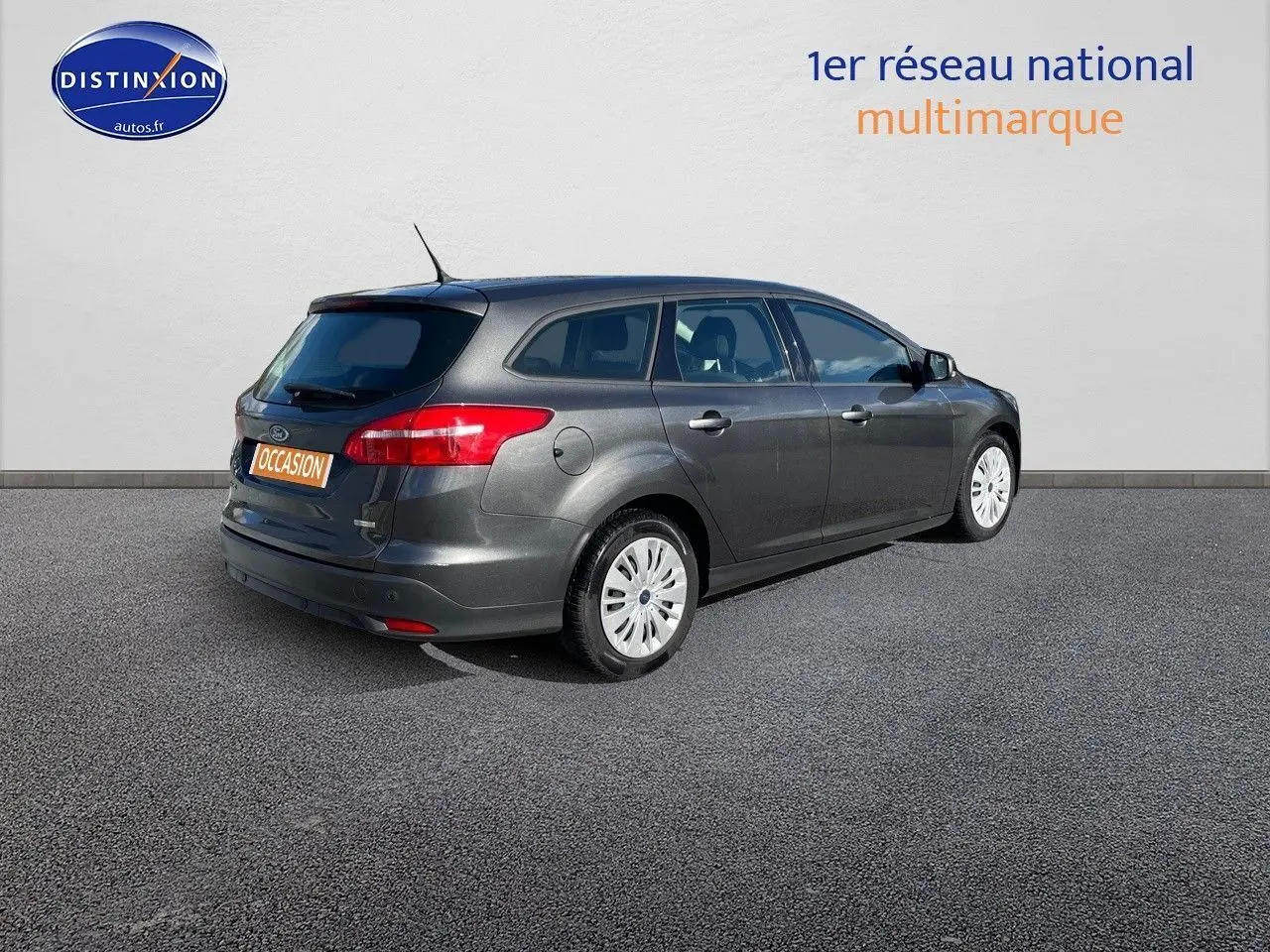 Ford Focus SW gris magnetic metal vue 3/4 arrière droit, break 5 portes en extérieur sur sol bitumé.