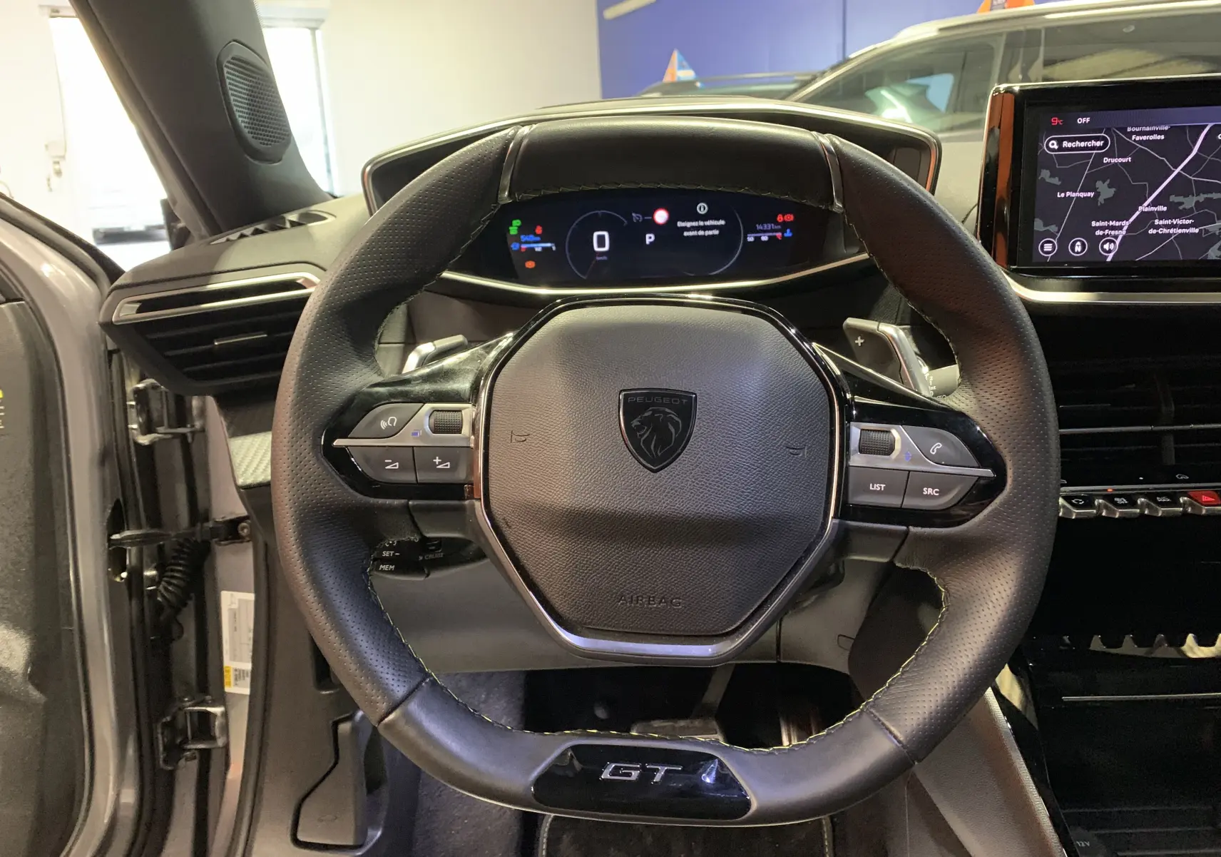 Vue rapprochée du volant cuir noir GT et du tableau de bord numérique du Peugeot 2008 gris 2023.