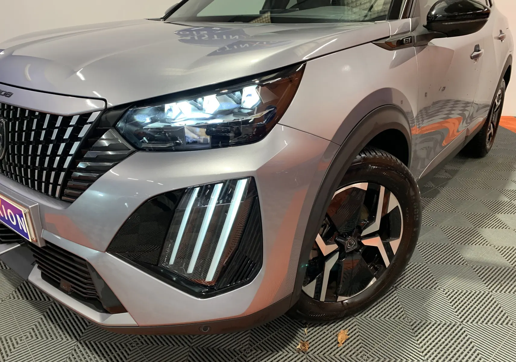 Vue 3/4 avant droit d'un Peugeot 2008 gris 2023 avec phares LED et jantes alliage noires distinctives.