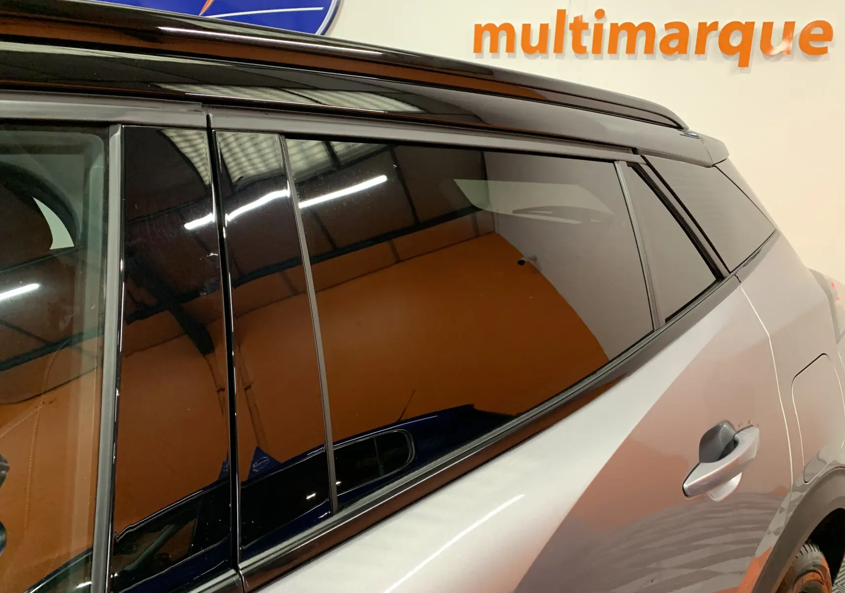 Vue latérale droite du Peugeot 2008 gris 2023, mettant en valeur la porte arrière et la finition noire brillante autour des vitres.