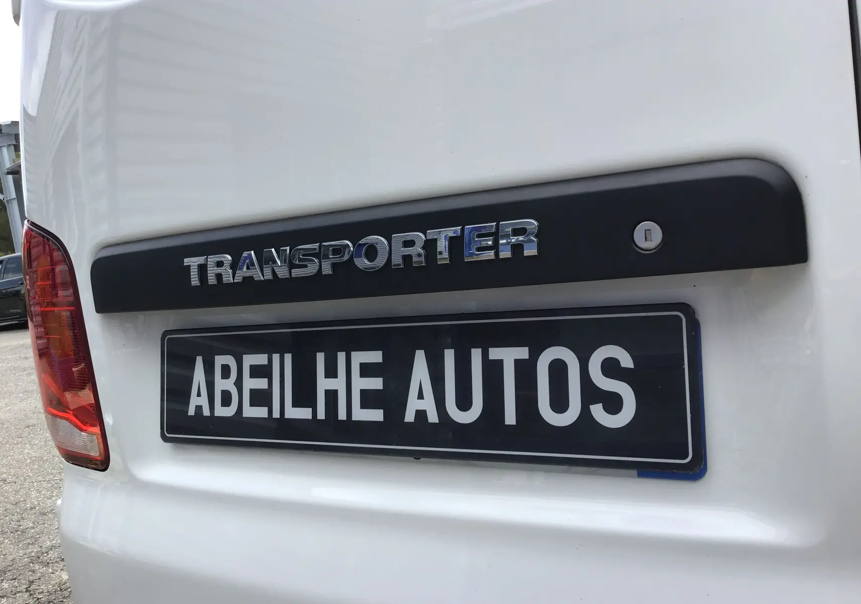 Gros plan sur l'arrière blanc du Volkswagen Transporter 6.1 avec logo TRANSPORTER et plaque Abeilhe Autos.