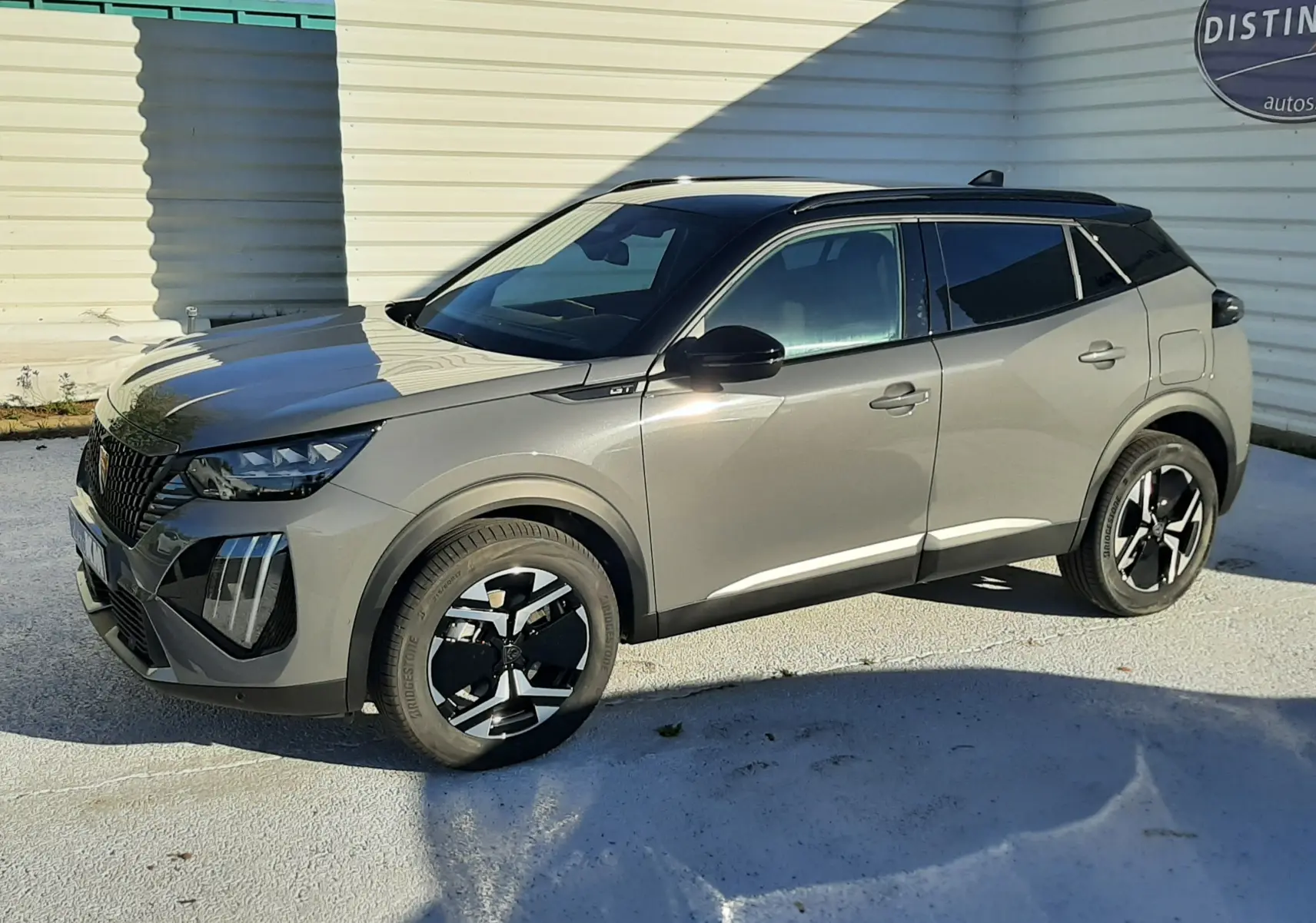 Peugeot 2008 gris selenium en vue 3/4 avant droit, avec toit noir et jantes alliage bicolores distinctives.