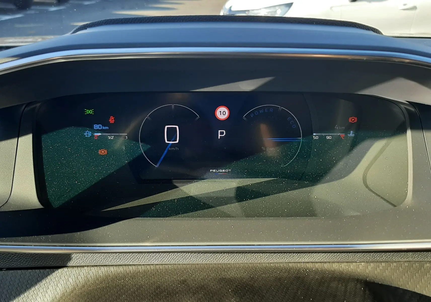 Tableau de bord numérique du Peugeot 2008 1.2 Hybrid 145ch GT, affichant vitesse à zéro et mode parking, intérieur noir.