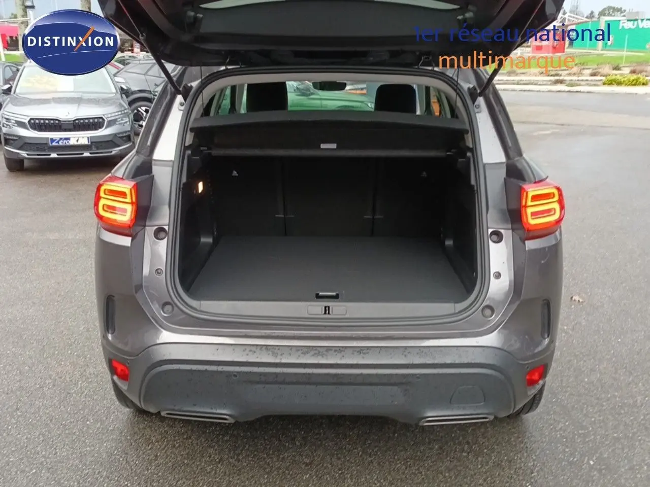 Vue arrière d'un Citroën C5 Aircross hybride rechargeable gris platinium avec coffre ouvert et feux arrière allumés.