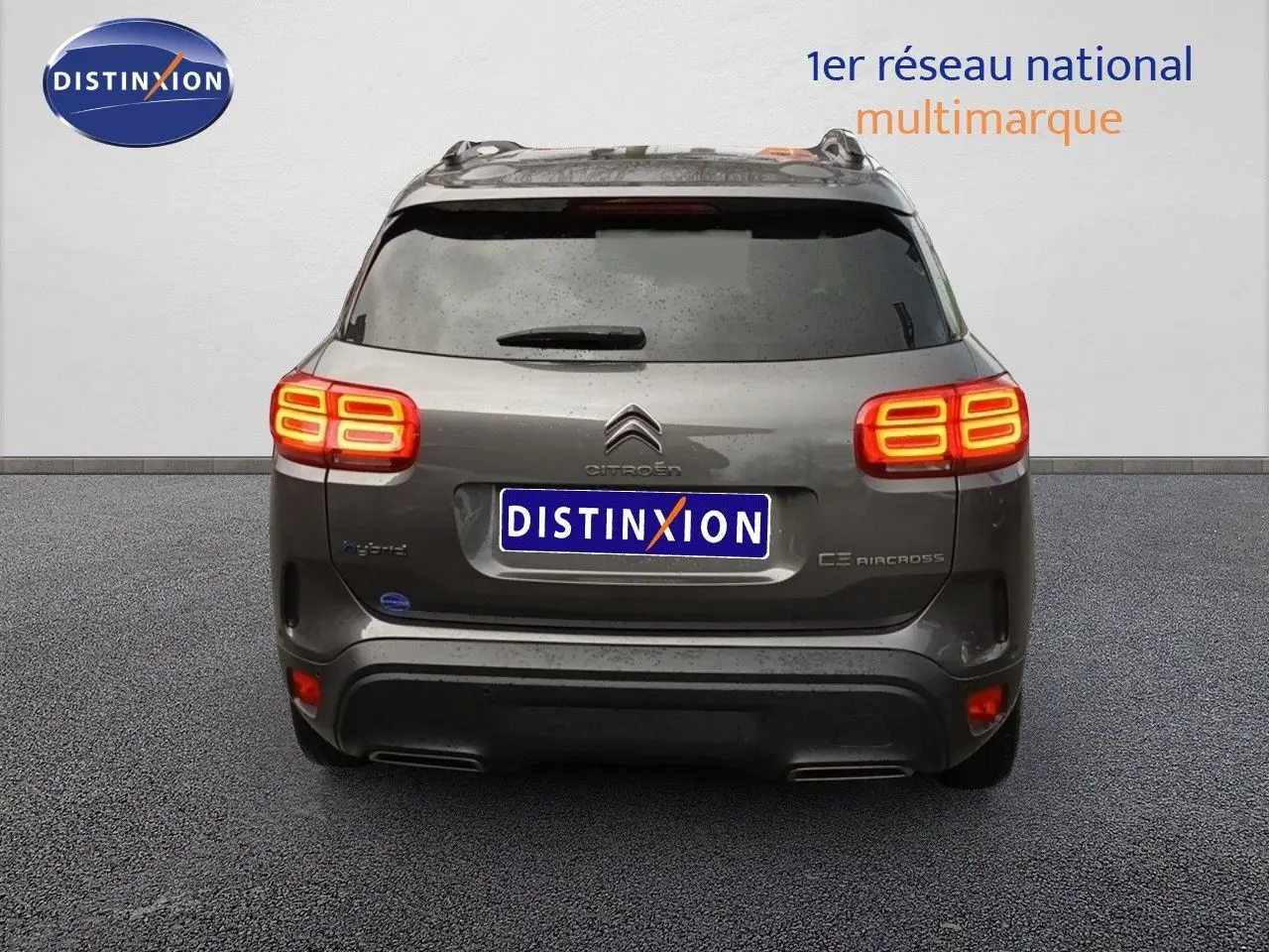 Vue arrière d'un Citroën C5 Aircross hybride rechargeable gris platinium avec feux allumés, en stationnement.