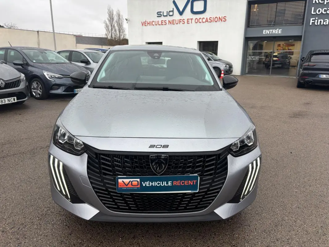 Vue avant frontale d'une Peugeot 208 gris métallisé avec feux diurnes LED en forme de griffes et calandre noire distinctive.