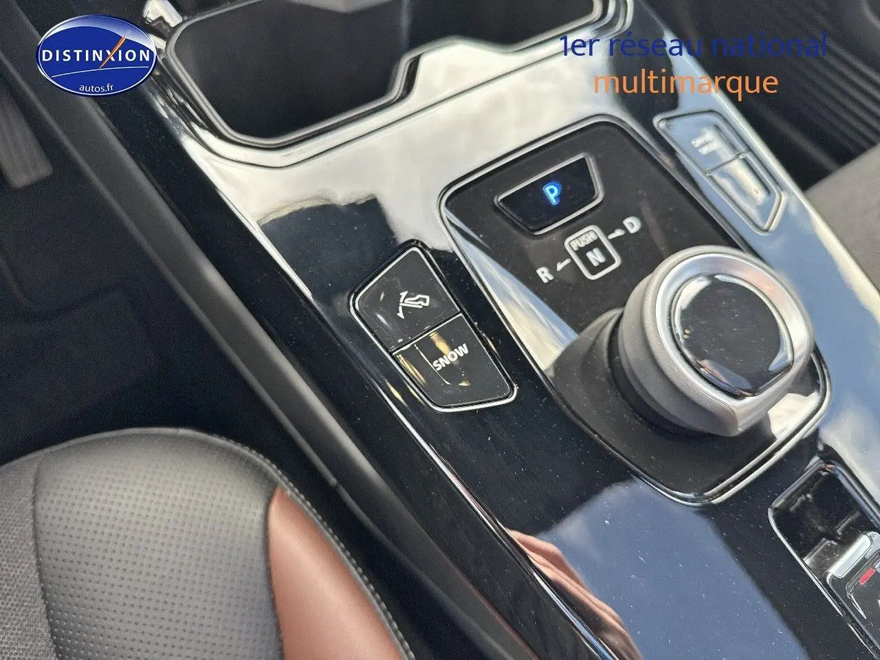 Gros plan sur la console centrale noire brillante du Suzuki Vitara 2026, avec molette de boîte auto et siège cuir noir/marron visible.