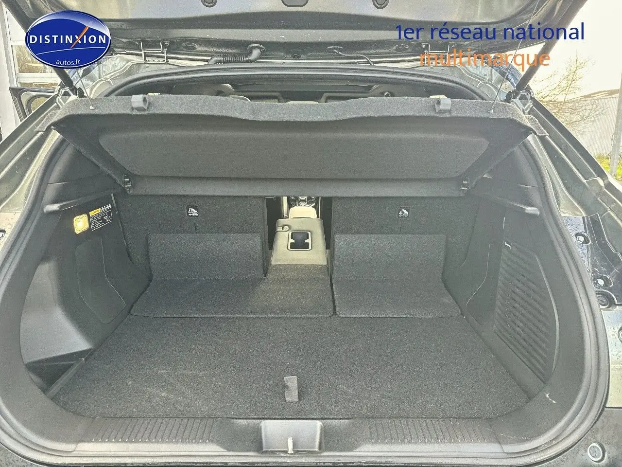 Coffre ouvert du Suzuki Vitara 2026 vert Land Breeze avec toit noir, montrant banquette arrière rabattue et espace de chargement.