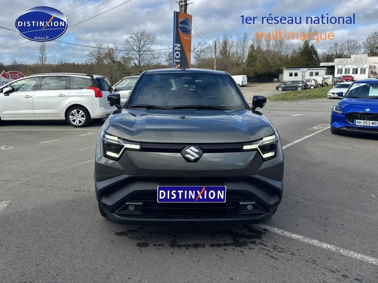 Vue de face du Suzuki Vitara 2026 gris foncé avec toit noir, sur parking extérieur sous ciel nuageux.