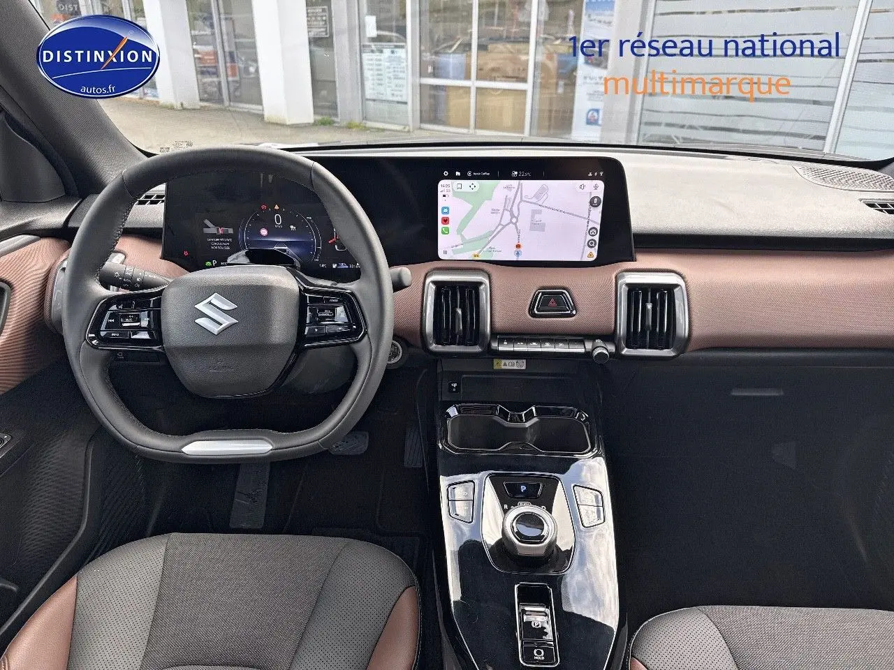 Vue intérieure avant du Suzuki Vitara 2026 avec tableau de bord marron et noir, écran tactile GPS et volant multifonction.