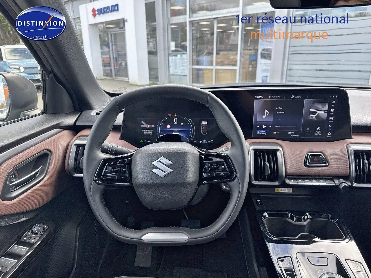 Vue intérieure avant centrée sur le volant Suzuki et tableau de bord avec écran tactile, garniture marron et noir.