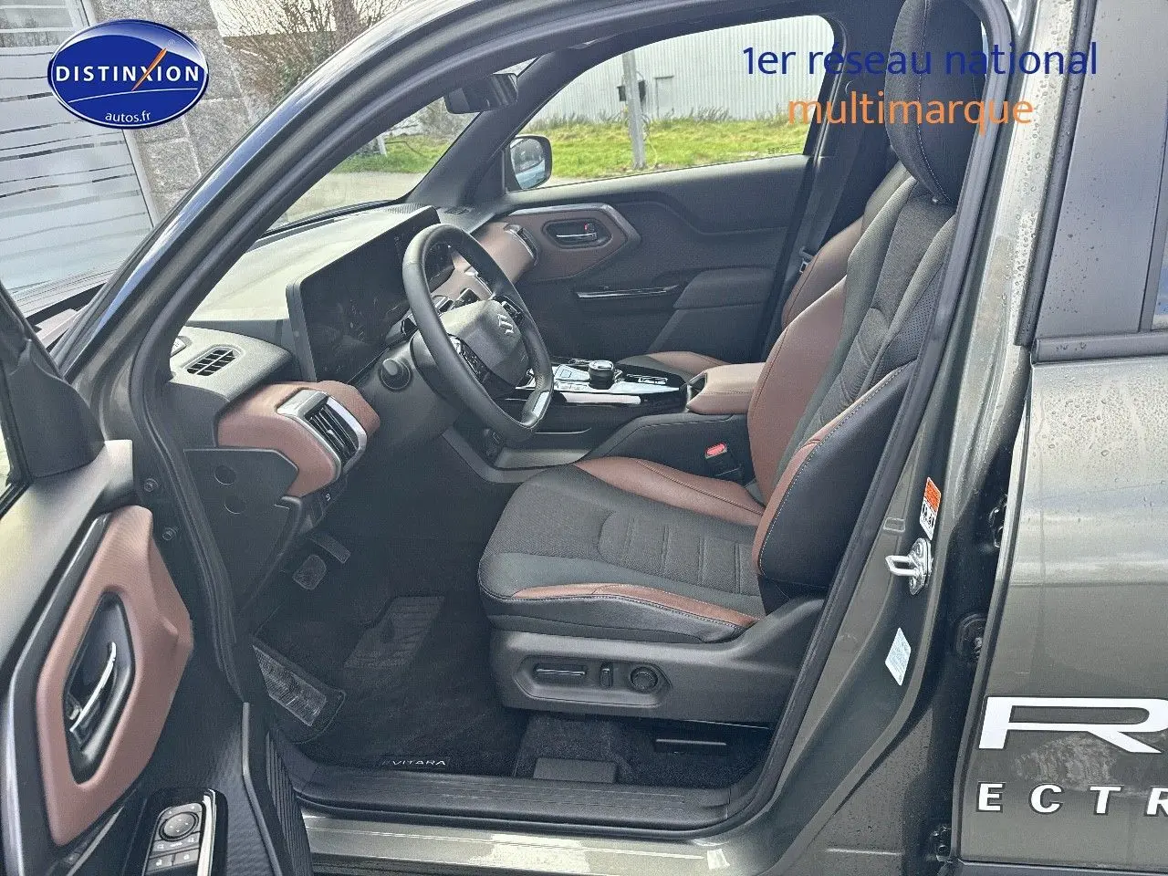 Vue intérieure côté conducteur du Suzuki Vitara 2026 vert Land Breeze avec sellerie tissu/cuir marron et noir.