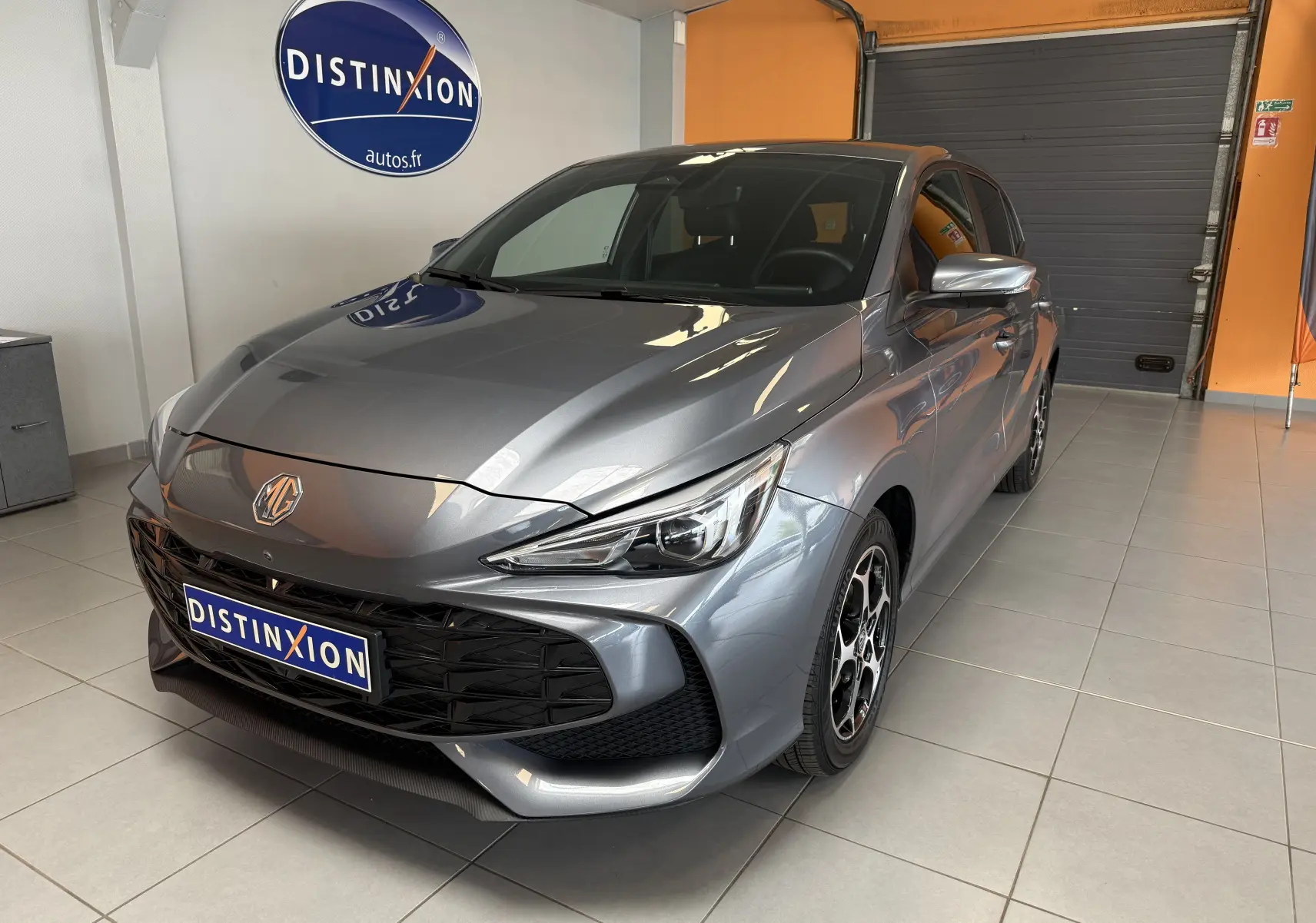 Vue 3/4 avant d'une MG3 gris Hampstead avec calandre noire et jantes bicolores en showroom.