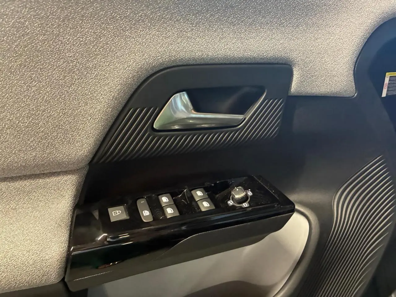 Gros plan sur la poignée de porte côté gauche du Citroën C5 Aircross 2026 vert, avec commandes de vitres et rétroviseurs.