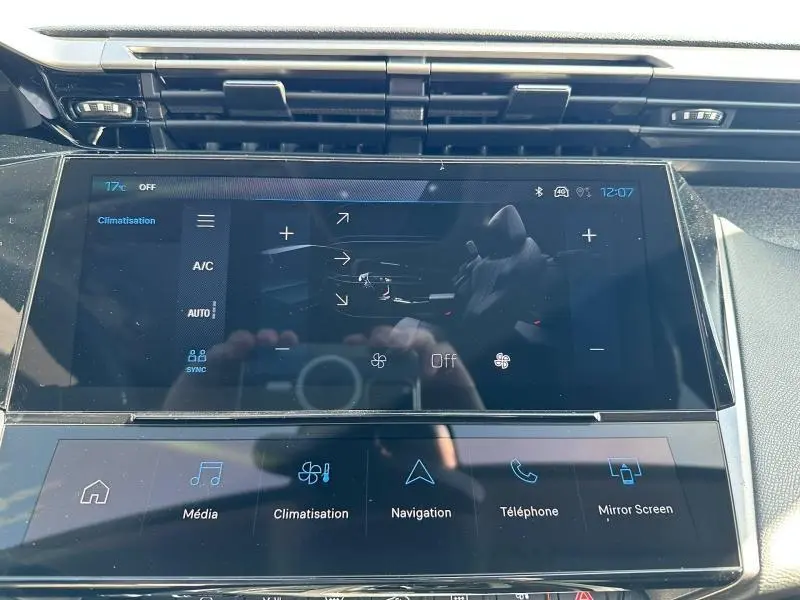 Écran tactile central de la Peugeot 308 bleu, affichant les commandes de climatisation et multimédia en gros plan.