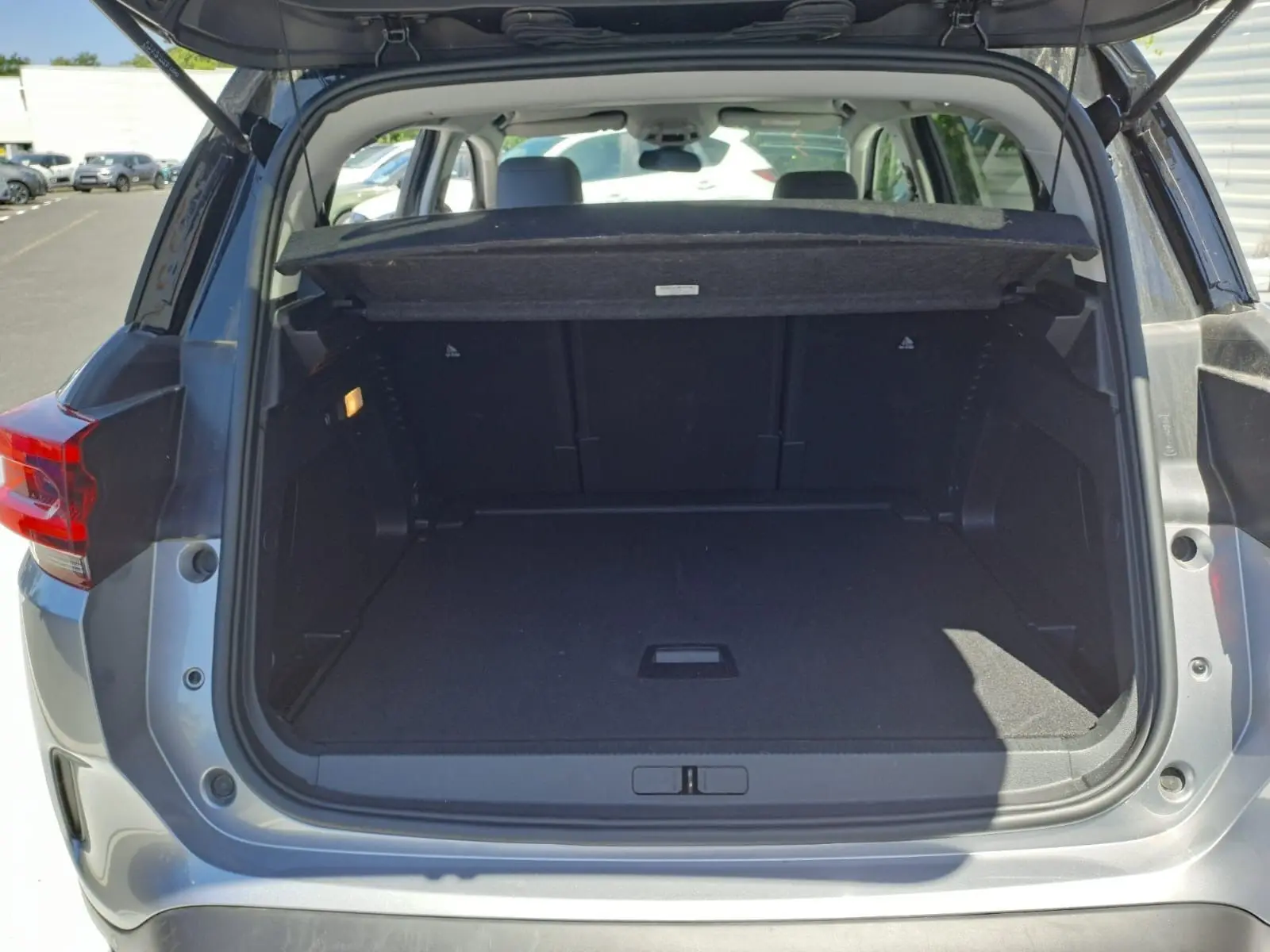 Coffre ouvert vu de l'arrière d'un Citroën C5 Aircross gris Artense avec toit noir, montrant un espace de chargement vide.