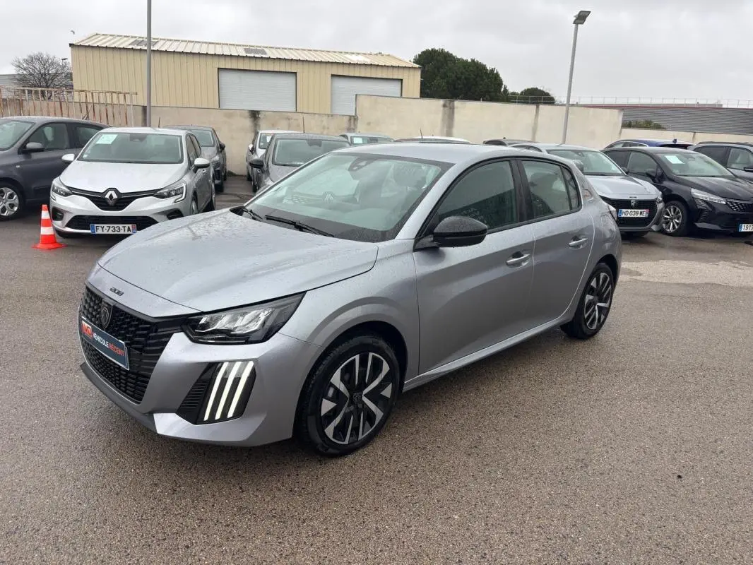 Peugeot 208 Hybrid gris vue 3/4 avant droit, avec feux diurnes LED verticaux et jantes 16 pouces.