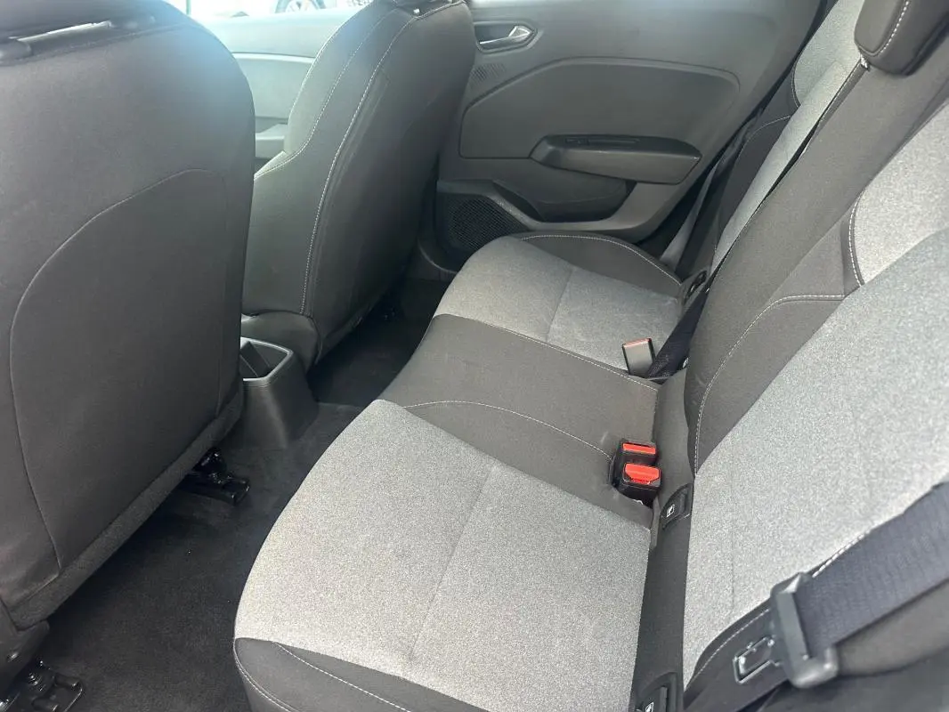 Vue intérieure arrière côté droit montrant les sièges bicolores gris et noir de la Renault Clio V dCi 100 Evolution 2025.