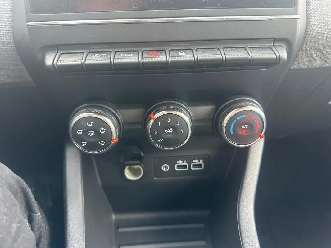 Vue rapprochée du tableau de bord de la Renault Clio V dCi 100 Evolution 2025, montrant les commandes de climatisation manuelle.