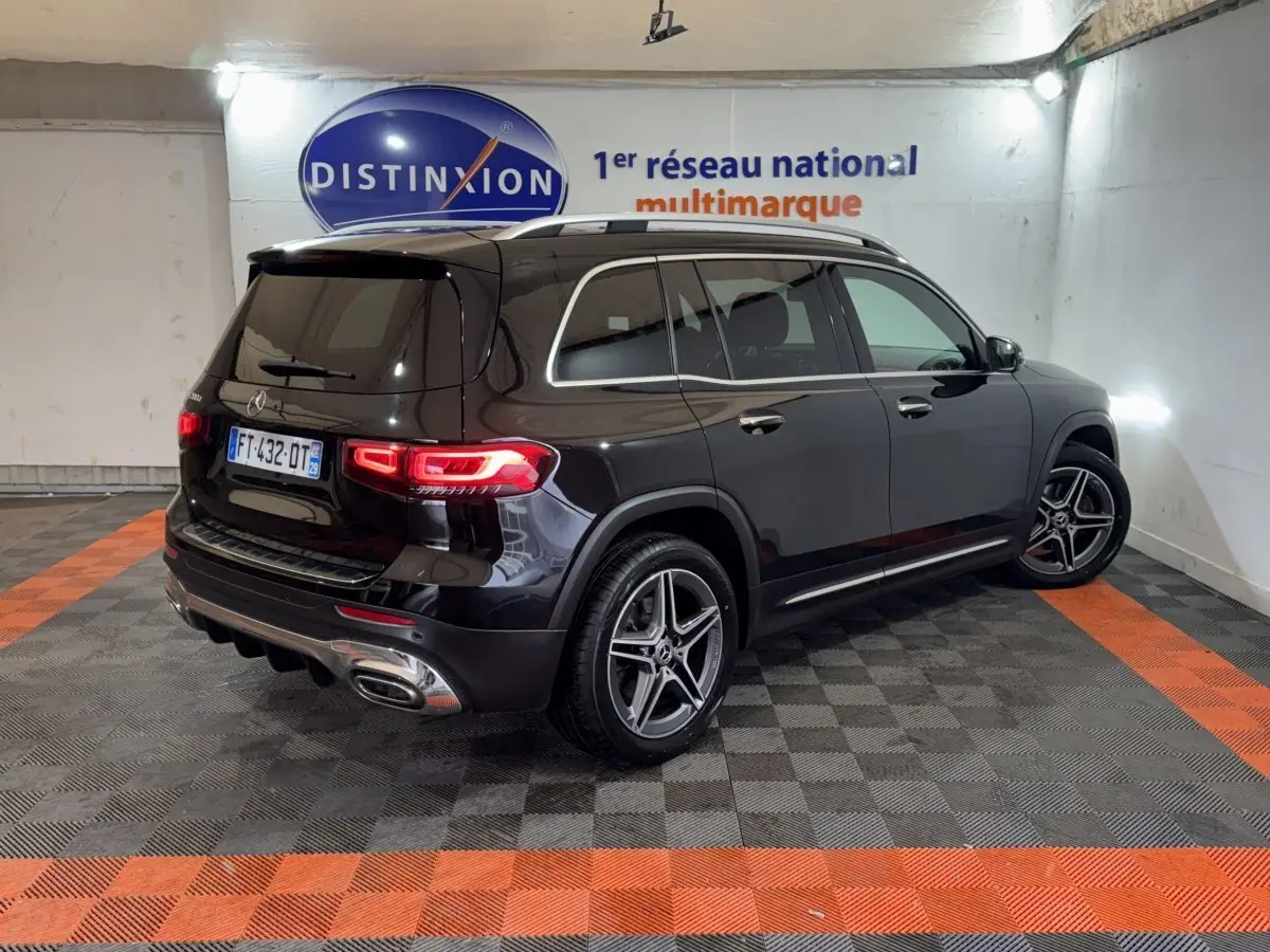 Vue 3/4 arrière droite d’un Mercedes GLB 200 d AMG Line noir, avec jantes AMG et feux arrière LED allumés.
