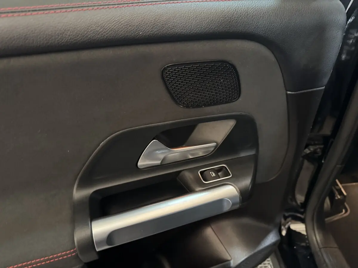 Détail de la porte intérieure côté gauche du Mercedes GLB 200 d AMG Line noir, avec poignée argentée et commande de fenêtre.