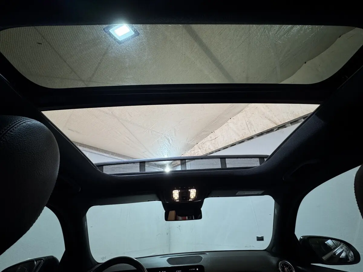 Vue intérieure du toit ouvrant panoramique du Mercedes GLB 200 d AMG Line noir, avec tableau de bord et rétroviseur central visibles.