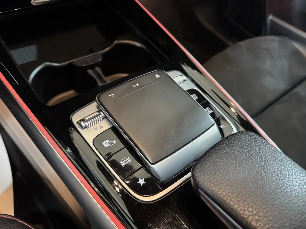 Gros plan sur la console centrale noire du Mercedes GLB 200 d AMG Line, mettant en valeur le pavé tactile et les boutons de contrôle.