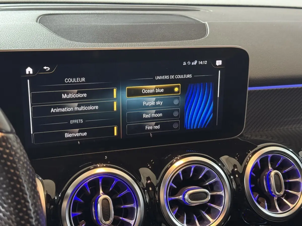 Détail de l’écran tactile central et des aérateurs ronds avec éclairage bleu intérieur du tableau de bord Mercedes GLB 200 d AMG Line.