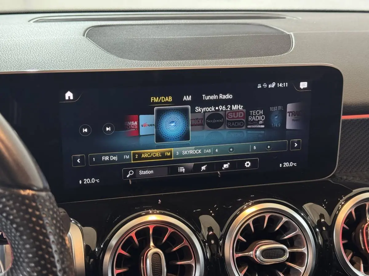 Vue rapprochée de l’écran tactile central et des aérateurs ronds chromés du tableau de bord noir du Mercedes GLB 200 d AMG Line.