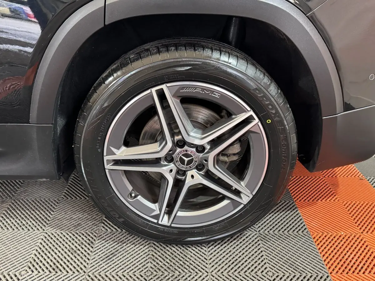 Gros plan sur la roue avant droite du Mercedes GLB 200 d AMG Line noir, mettant en valeur la jante AMG à cinq branches.