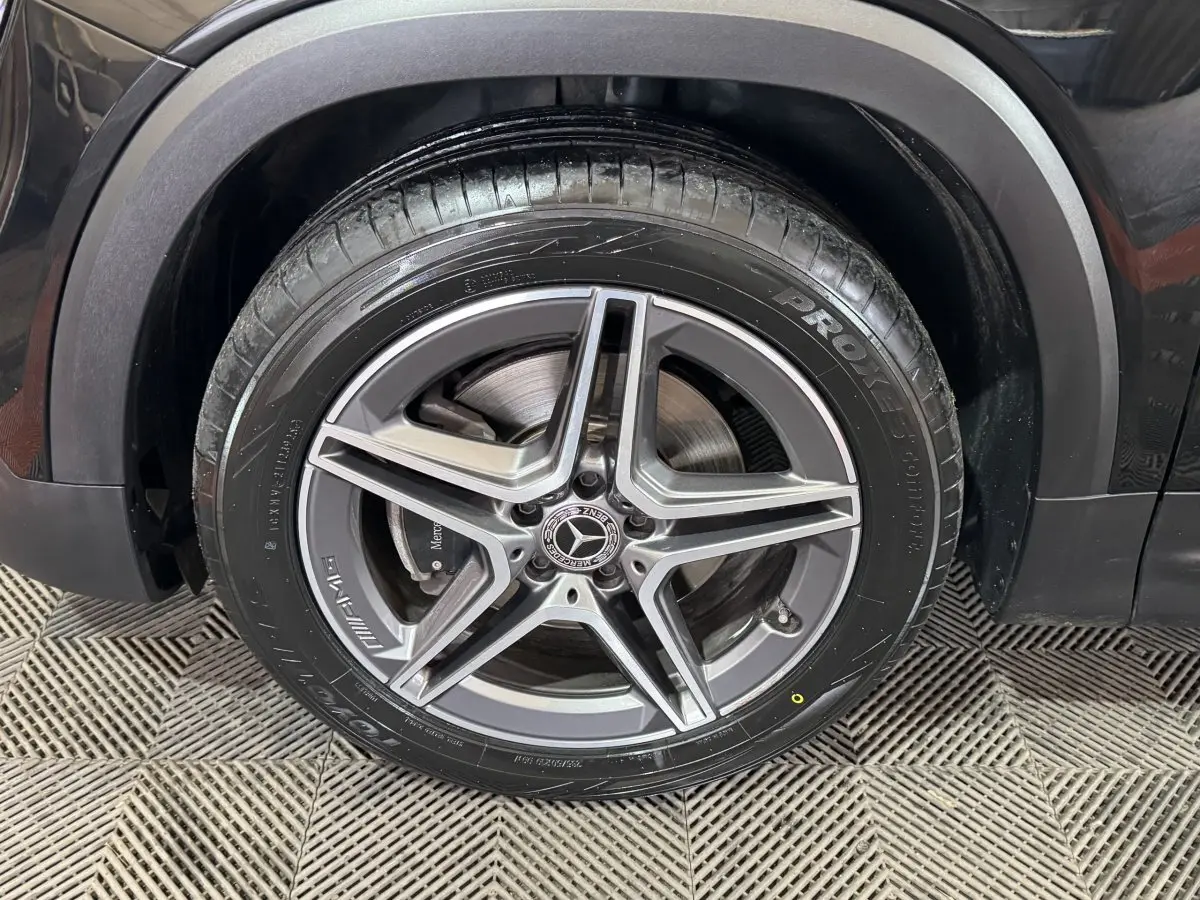 Gros plan sur la roue avant droite noire du Mercedes GLB 200 d AMG Line avec jante AMG cinq branches.