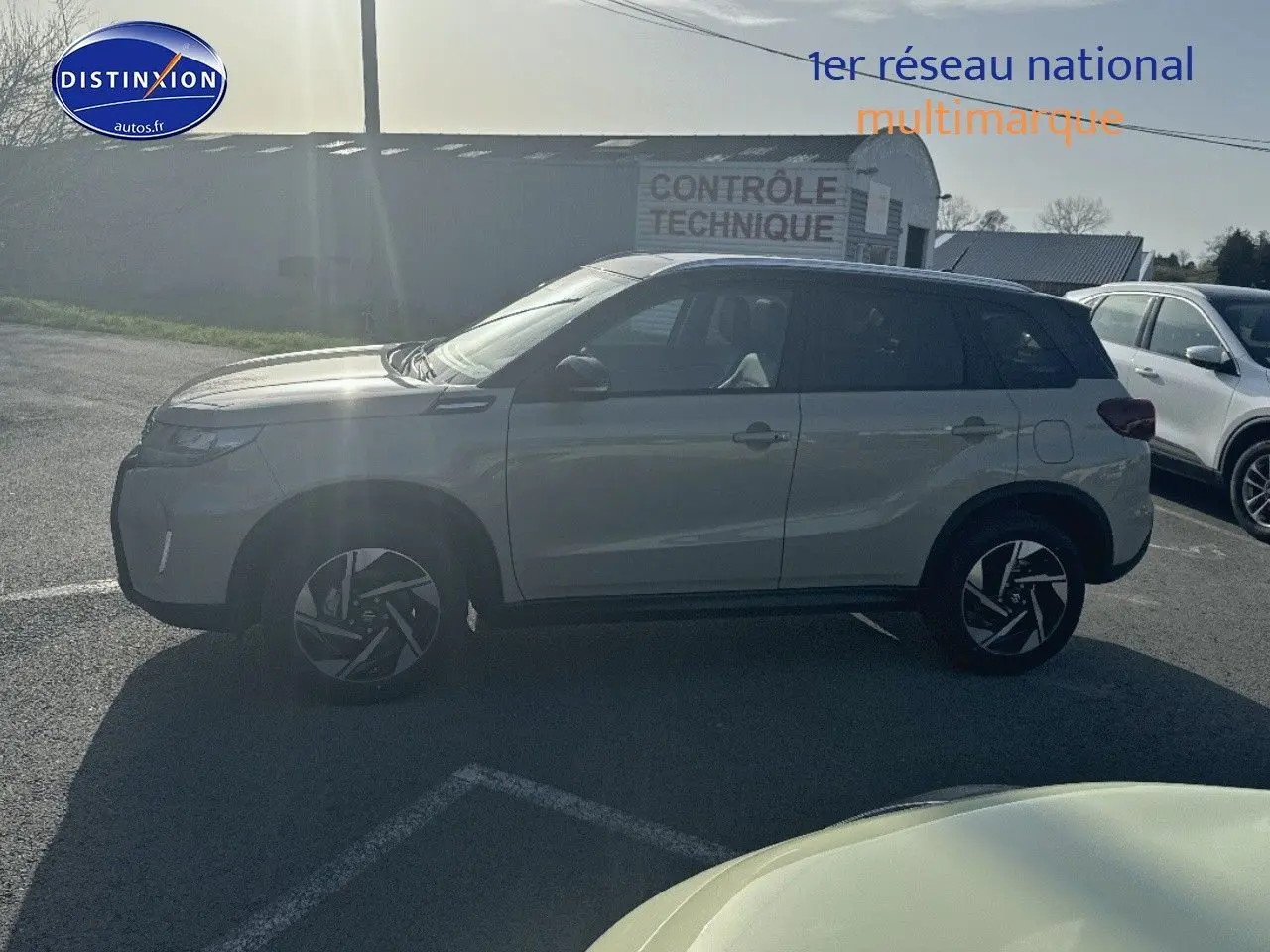 Suzuki Vitara 2026 vue de profil côté gauche, peinture bicolore ivoire et toit noir, jantes alu stylisées visibles.