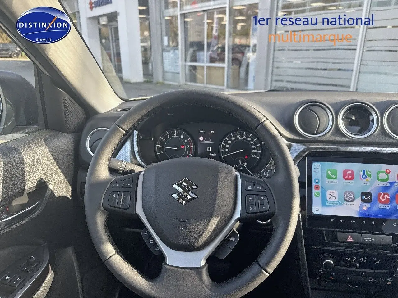 Vue intérieure centrée sur le volant cuir multifonction du Suzuki Vitara 1.4 Boosterjet Hybrid avec écran tactile et tableau de bord.