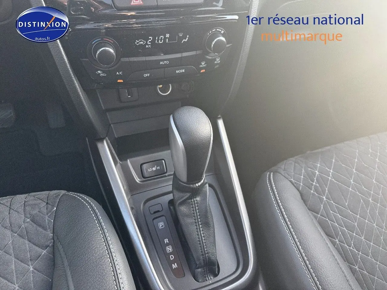 Vue rapprochée de la console centrale du Suzuki Vitara 2026, levier de boîte auto et sièges en suédine noire.