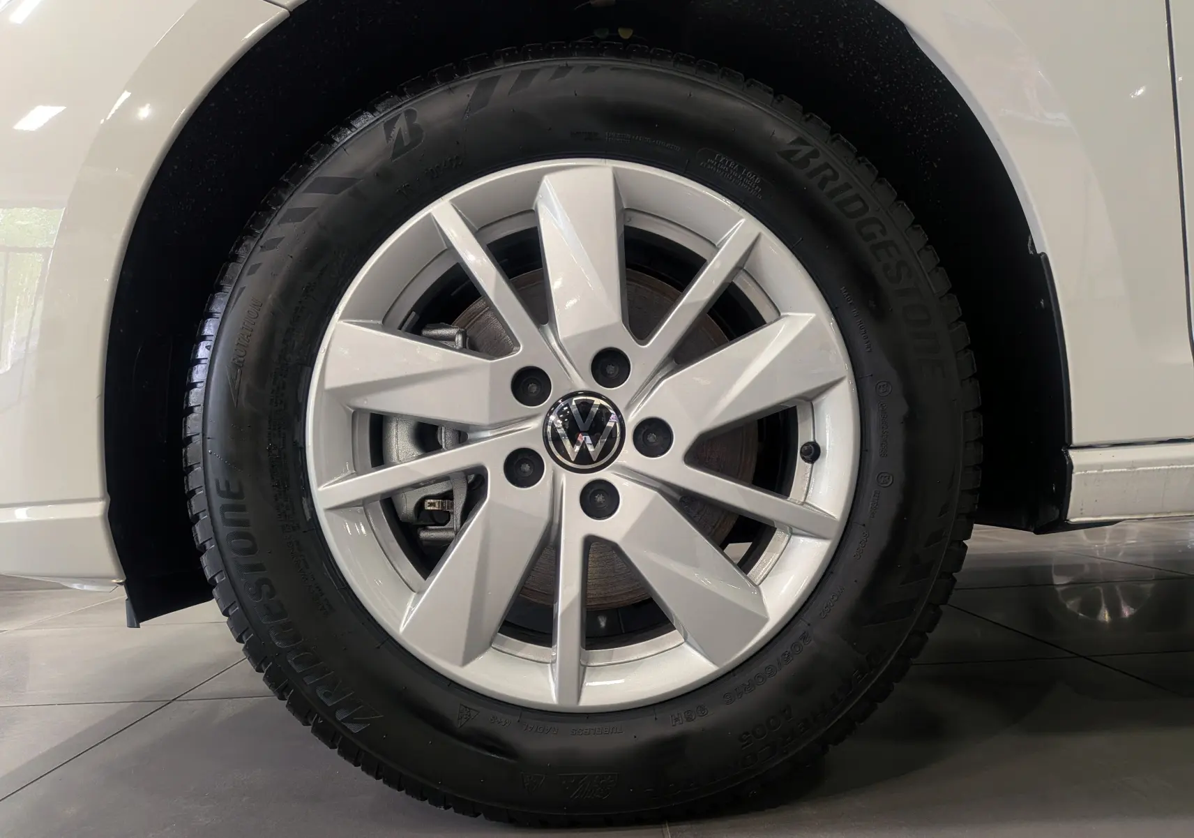 Gros plan sur la roue avant gauche blanche d’un Volkswagen Caddy 2.0 TDI 2025 avec jante alliage et pneu Bridgestone.