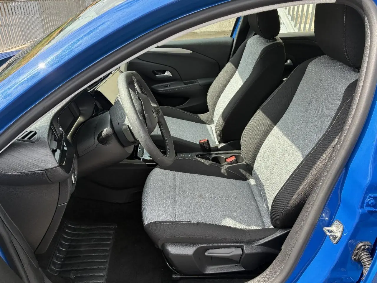Vue intérieure côté conducteur d'une Opel Corsa 2025 bleu vif, montrant les sièges tissu bicolore et le volant.