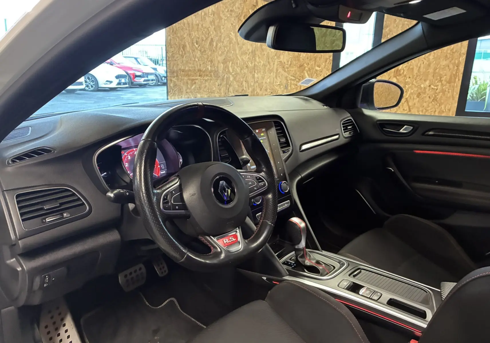 Vue intérieure côté conducteur de la Renault Mégane IV RS 280 EDC6 avec volant sport noir et détails rouges.